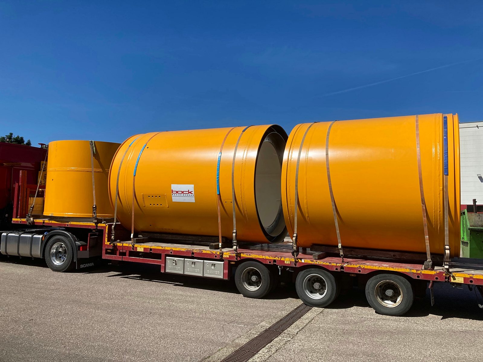 Versandfertige lackierte Großbauteile auf dem Tieflader, für den Transport gezurrt – Bock Maschinenbau Lorch