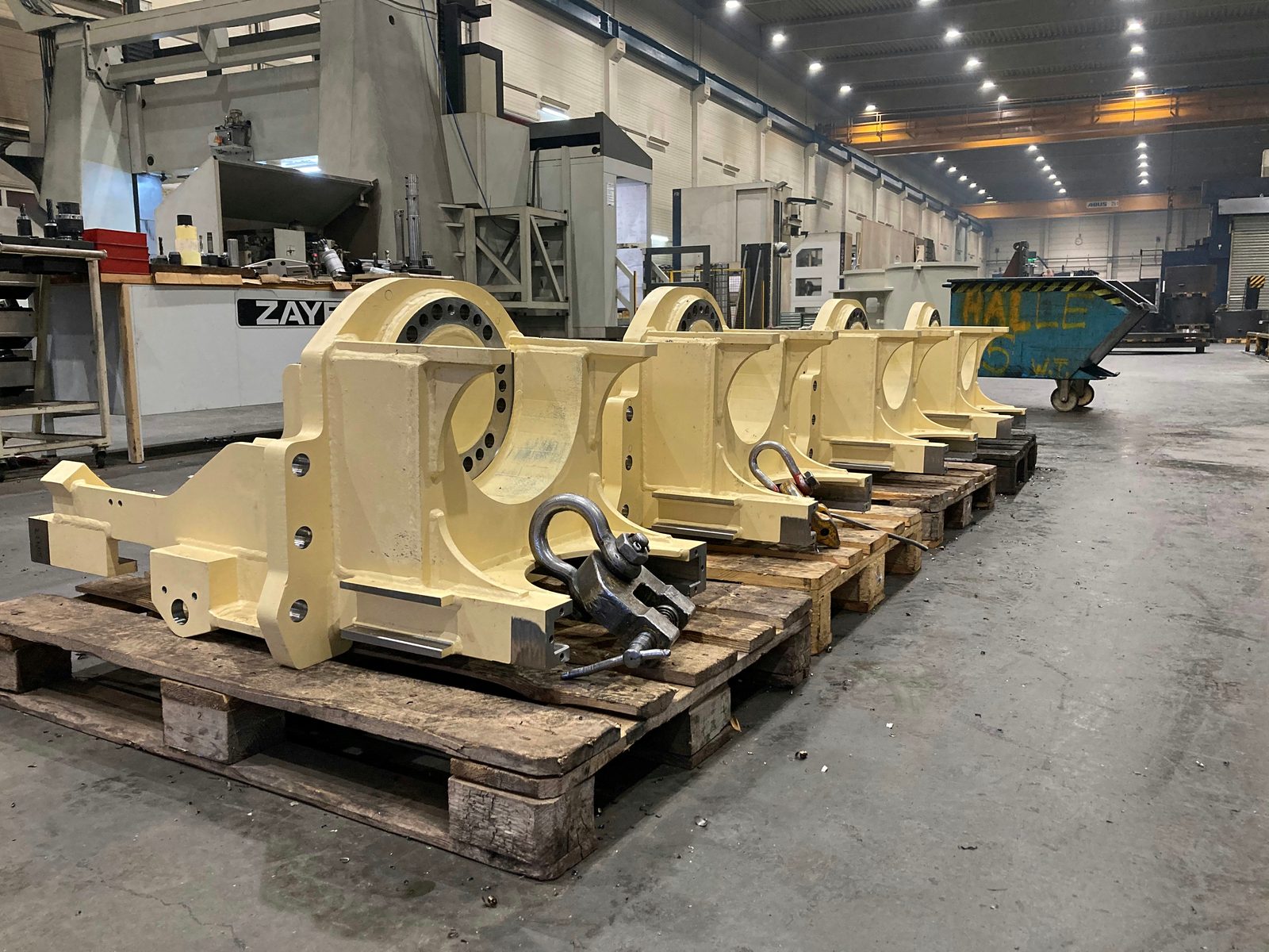 Four identical welded assemblies for construction machinery on pallets, bearing bore with bolt circle line-bored, seating faces milled bright, primed