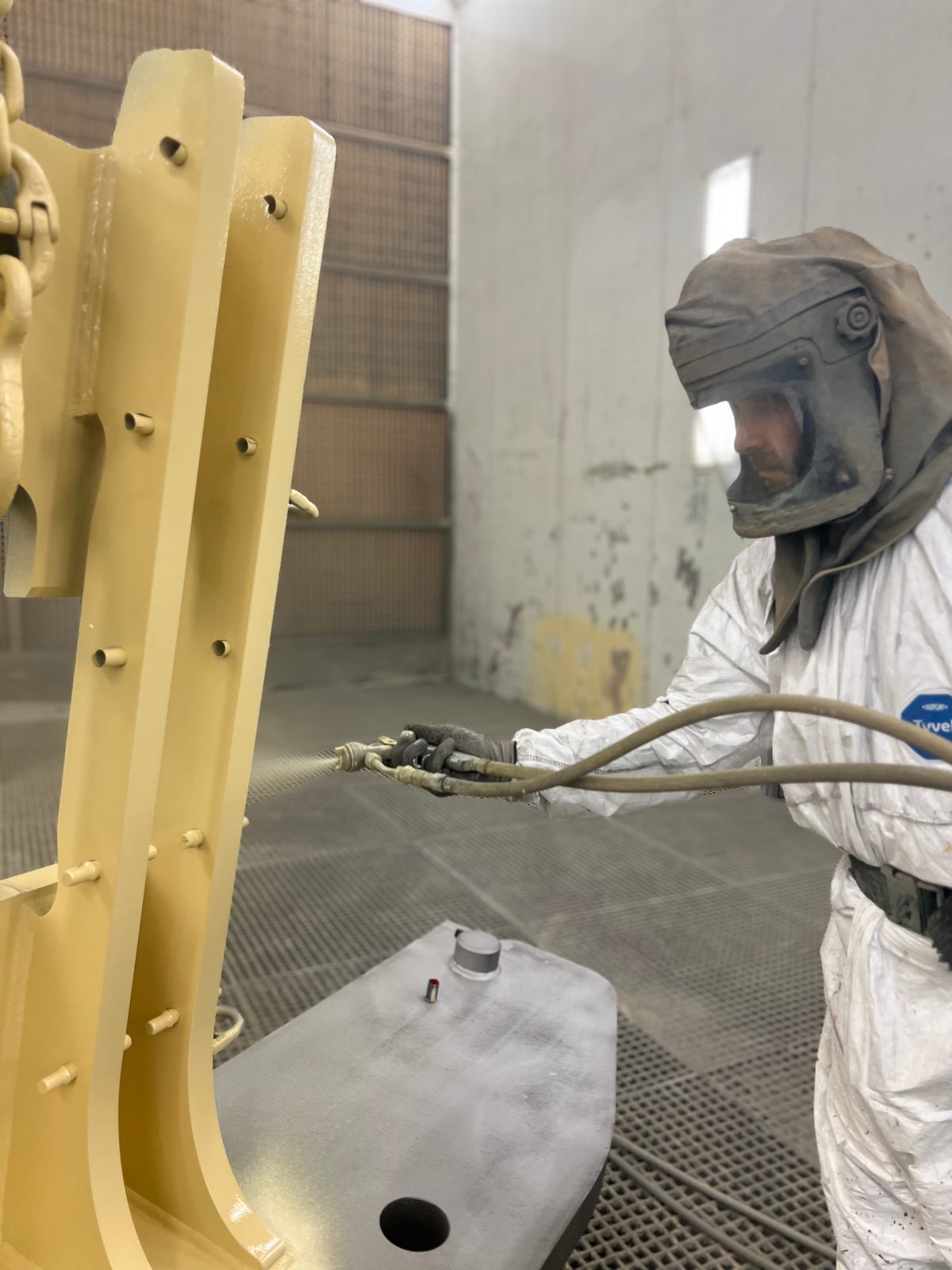 Industrial painter wet-spraying a welded steel structure – industrial coating to EN ISO 12944 with corrosion protection in the paint booth
