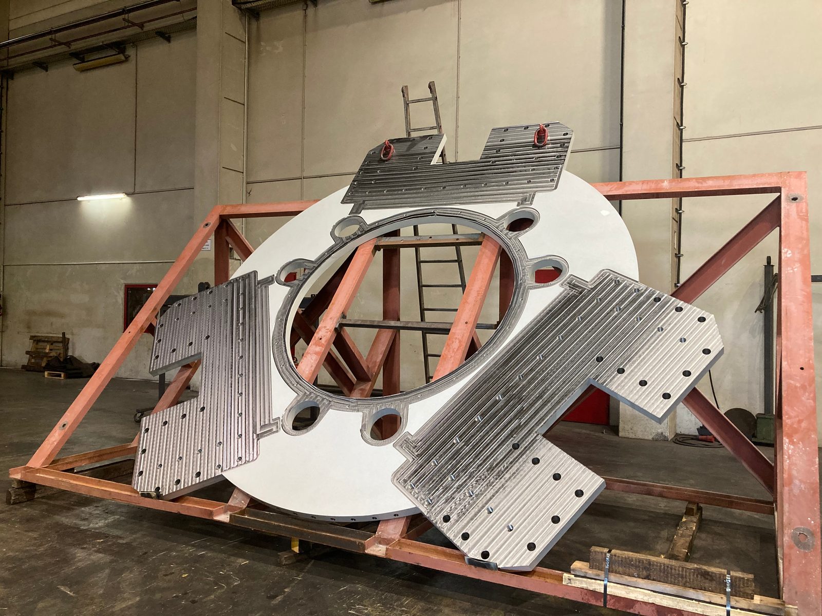 Grote gegronde ronde plaat met gefreesde middenopening en vier vlakgefreesde aansluitplaten met gatpatroon op een transportframe
