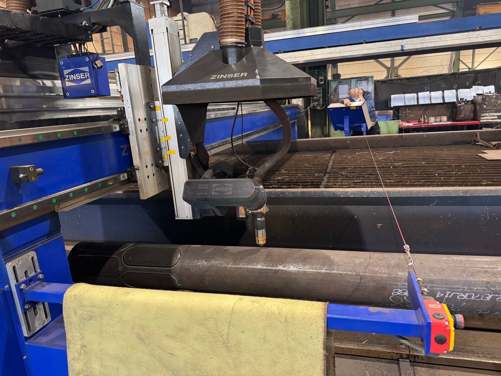 CNC-portal från Zinser med plasmabrännare över ett långt stålrör med flera långhålsurtag – alternativ till rörlaser