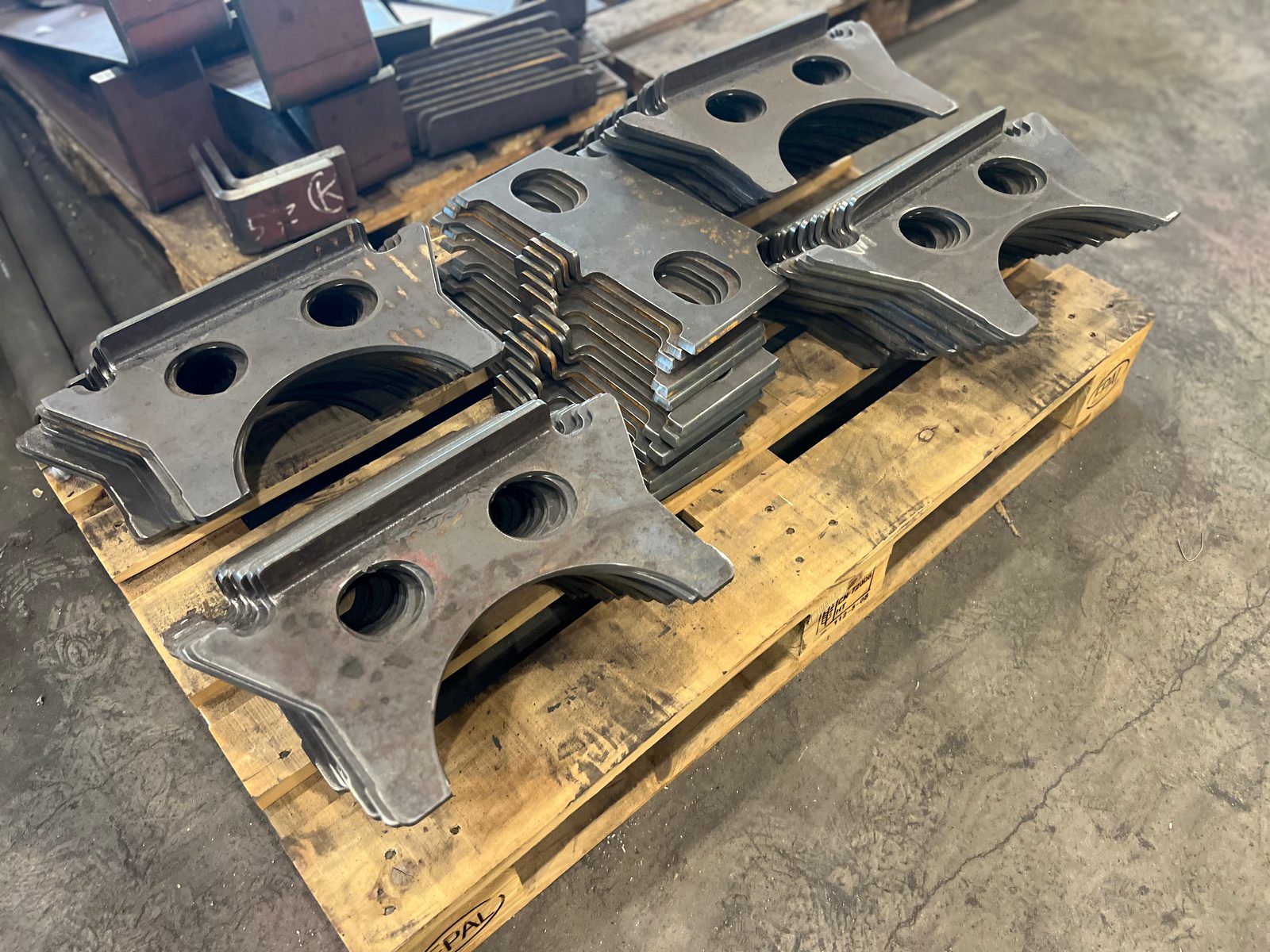 Staplade konsoler i plasmaskuren stålplåt med var sin kantning, hål och halvrunt urtag på en pall